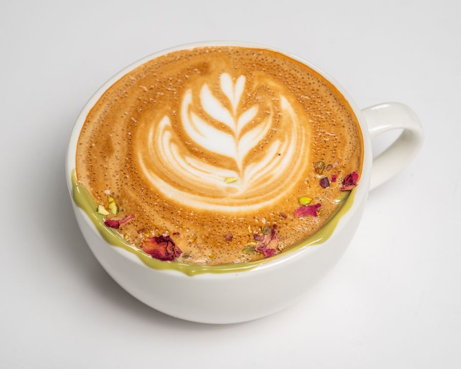 Rose pistachio latte with latte art, rose petals and pistachio